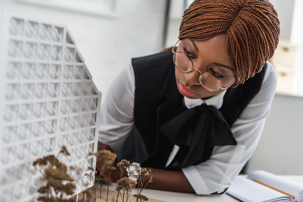 Afrikalı-Amerikalı kadın yetişkin mimar gözlük ve formal giyim inşaat proje üzerinde çalışan odaklı - Fotoğraf, Görsel
