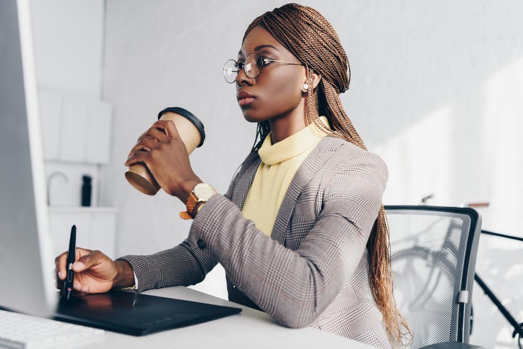 コンピューターの机に座って、コーヒーを飲みながら、グラフィック タブレットを使用して深刻なアフリカ系アメリカ人の大人実業家 - 写真・画像