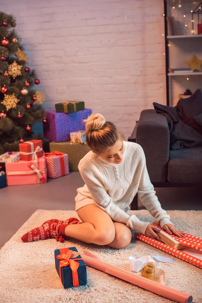 молода блондинка сидить і обгортає подарунки в різдвяний час
  - Фото, зображення