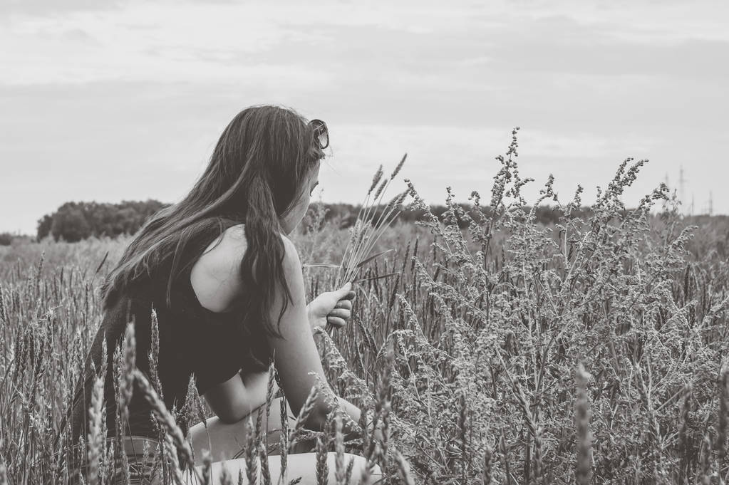 La niña cosecha espiguillas de trigo en el campo. Fotografía en blanco y negro
. - Foto, imagen