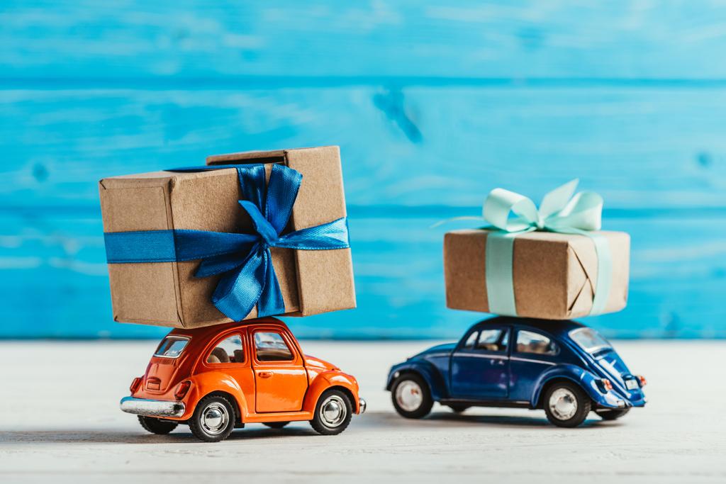 primer plano de los coches de juguete con cajas de regalo sobre fondo de madera azul
 - Foto, imagen