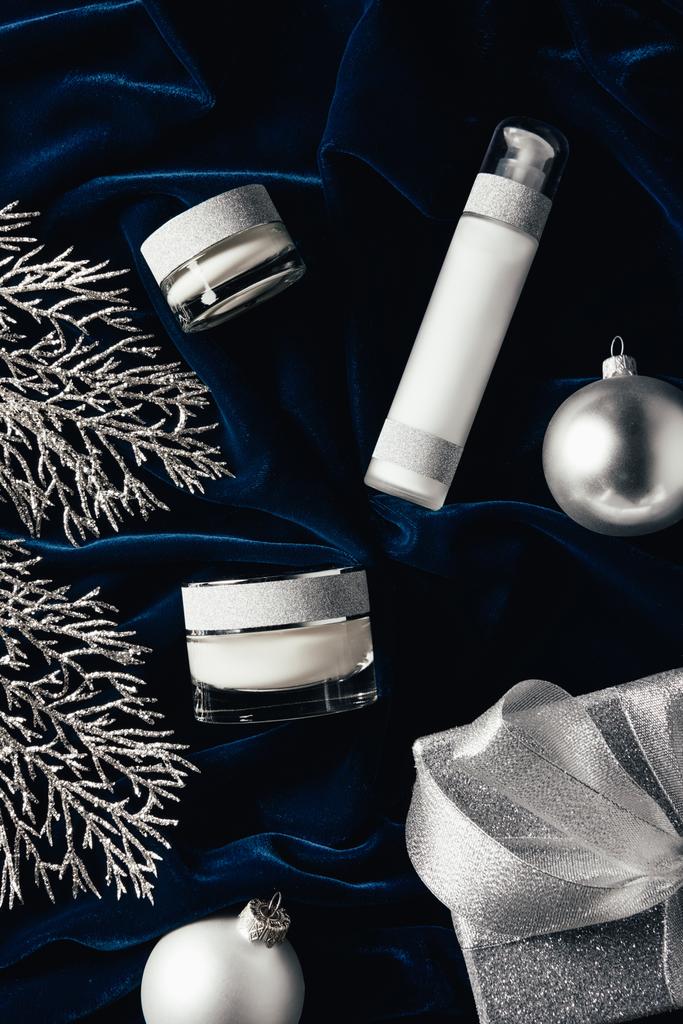 vue surélevée de la boîte cadeau, crème de beauté, lotion et boules de Noël en argent sur la surface en velours
  - Photo, image