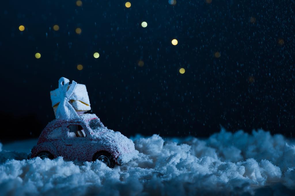 крупним планом знімок іграшкового автомобіля з подарунковою коробкою, що стоїть у снігу вночі, різдвяна концепція
 - Фото, зображення