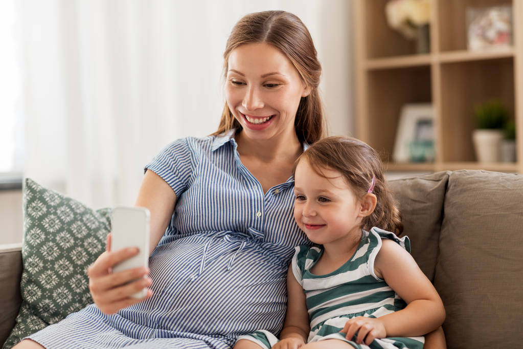 mãe grávida e filha com smartphone
 - Foto, Imagem