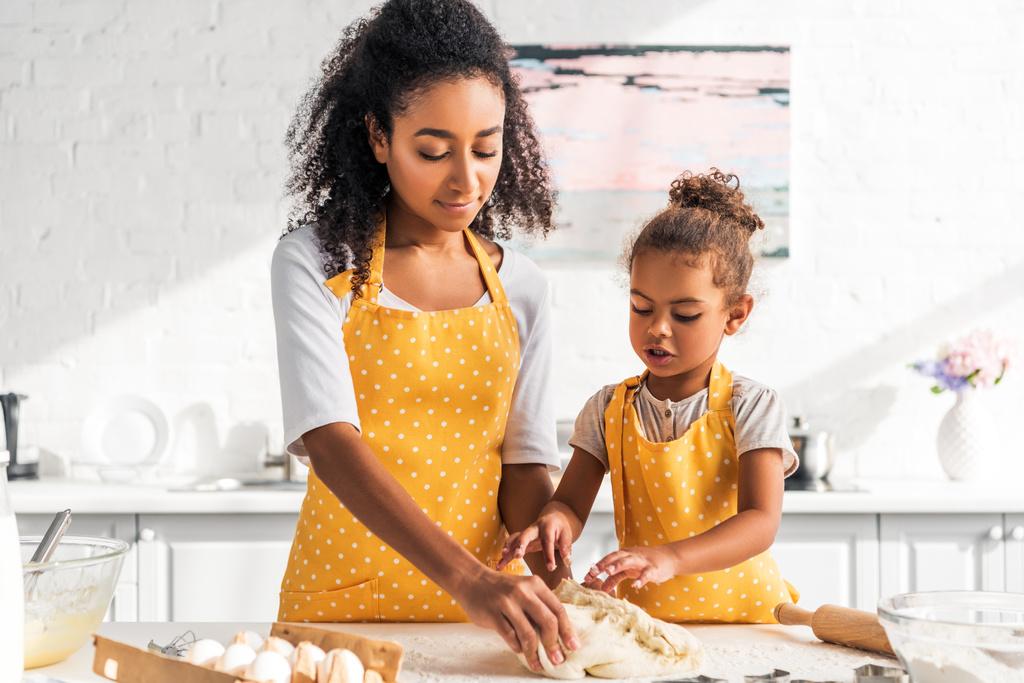 african american mother and daughter kneading dough in kitchen - Photo, Image