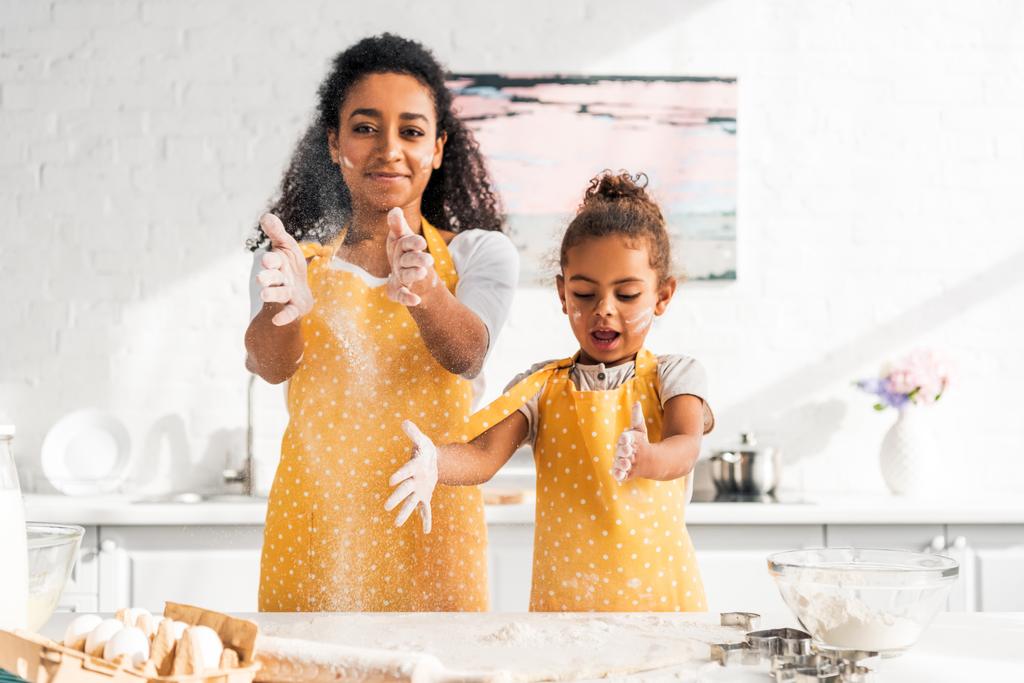 Αφρικανική αμερικανική μητέρα και κόρη ζύμη και τη διασκέδαση με το αλεύρι στην κουζίνα - Φωτογραφία, εικόνα