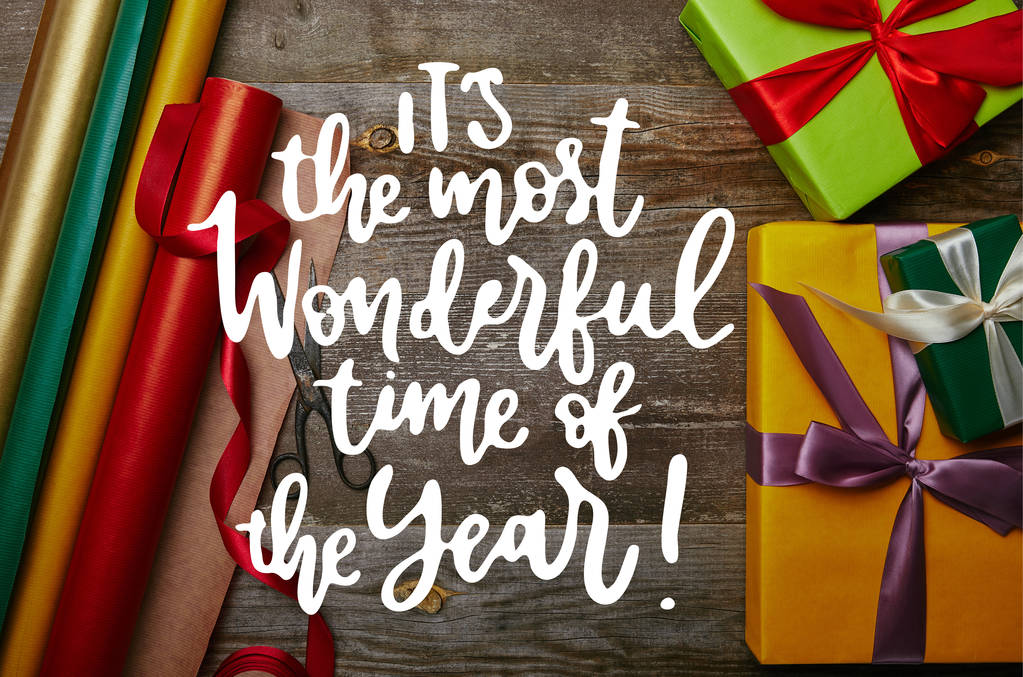 vue du dessus de l'arrangement des papiers d'emballage, des cadeaux de nouvel an avec des rubans et des ciseaux sur la table en bois avec "c'est la plus belle période de l'année" inspiration
  - Photo, image