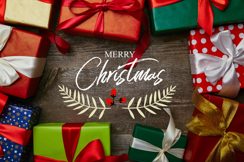 「メリー クリスマス」の文字で木の表面にリボンで別の包装紙に包まれたクリスマス プレゼントでフラット レイアウト - 写真・画像