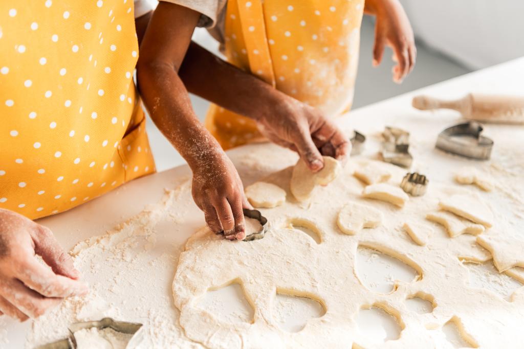 περικομμένη εικόνα των αφροαμερικάνων μητέρα και κόρη προετοιμασία μπισκότα με καλούπια στην κουζίνα - Φωτογραφία, εικόνα