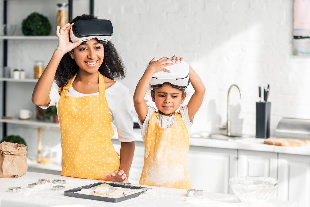 Mutter und Tochter bereiten Teig zu und tragen Virtual-Reality-Headsets in der Küche - Foto, Bild