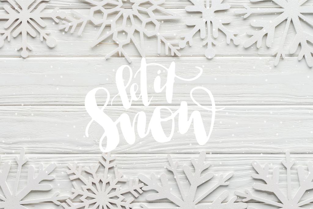 tendido plano con copos de nieve decorativos sobre fondo de madera blanca con letras de "déjalo nevar"
 - Foto, Imagen