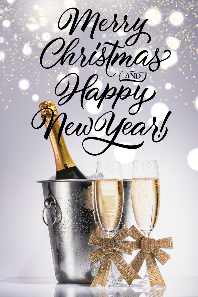 бутылка шампанского в ведре и бокалы шампанского на сером фоне с надписью "Счастливого Рождества и счастливого Нового года"
 - Фото, изображение