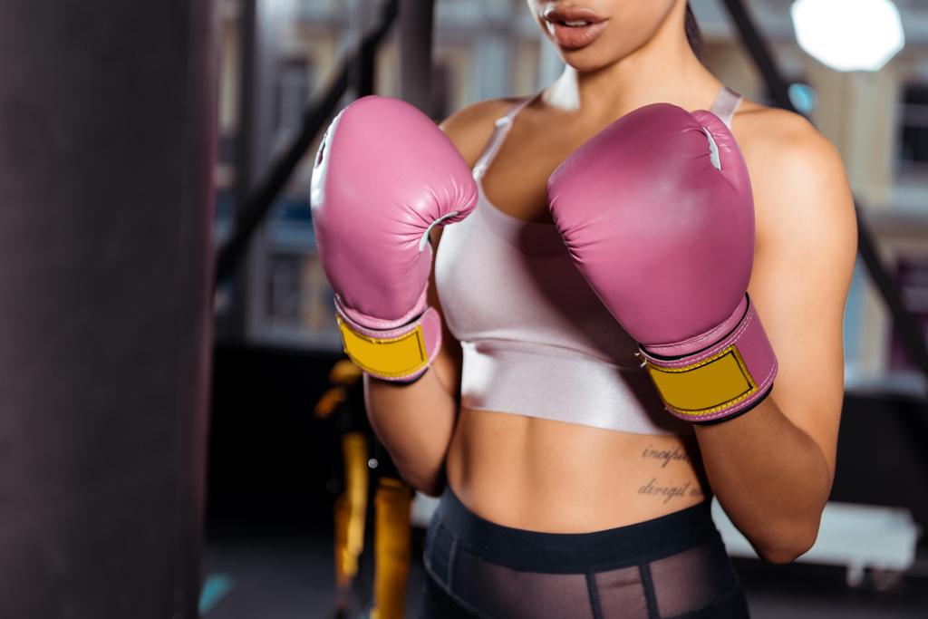 Partial view of strong girl in boxing gloves practicing boxing in gym  - Photo, Image