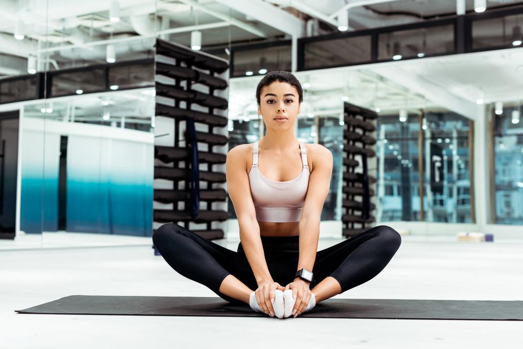 Atractiva joven mujer estirándose en el gimnasio en la alfombra de fitness
 - Foto, Imagen