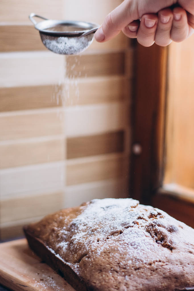 Домашний традиционный вишневый пирог, посыпанный сахарным порошком. Женщина посыпала порошок сахарной пудрой
 - Фото, изображение