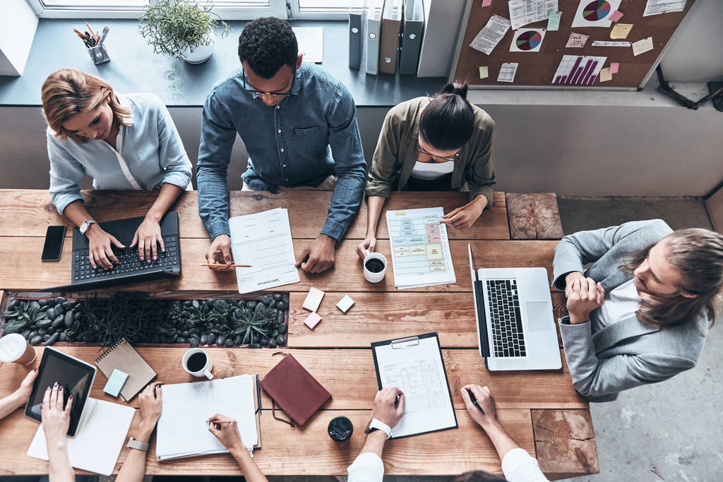 vista superior de pessoas de negócios brainstorming no escritório moderno na mesa de madeira com laptops, tablet digital e documentos
  - Foto, Imagem