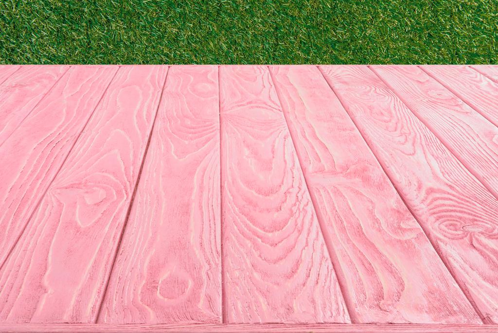  Oberfläche aus rosa Holzplanken auf grünem Gras Hintergrund - Foto, Bild