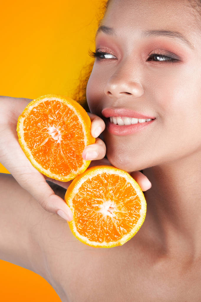 Молодая улыбающаяся черная девушка с чистой идеальной кожей с оранжевым крупным планом. Портрет красоты
 - Фото, изображение