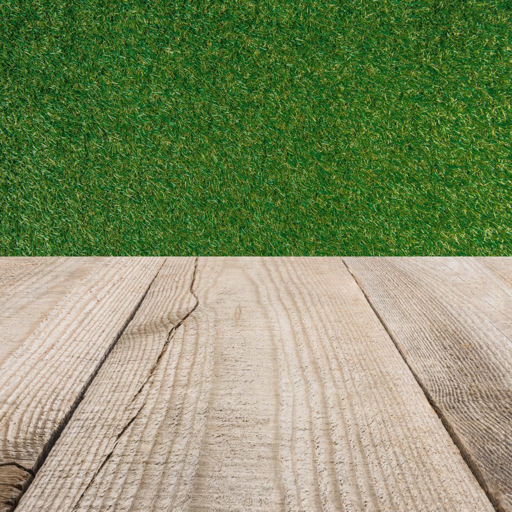 surface of beige wooden planks with green grass background - Photo, Image