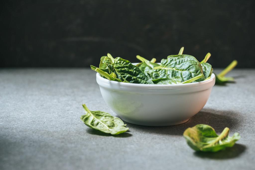 Vegetarian spinach leaves in white bowl on grey background - Photo, Image