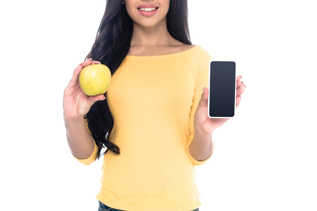 recadré blanc de sourire afro-américaine fille tenant pomme et smartphone avec écran blanc isolé sur blanc
 - Photo, image