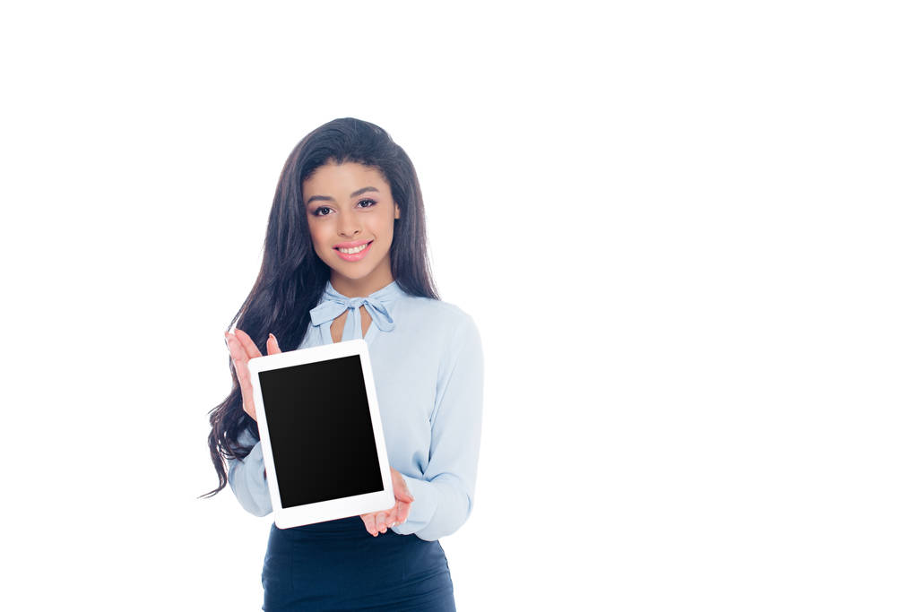 mooi Afrikaans Amerikaans meisje holding digitale tablet met zwart scherm en glimlachend op camera geïsoleerd op wit - Foto, afbeelding