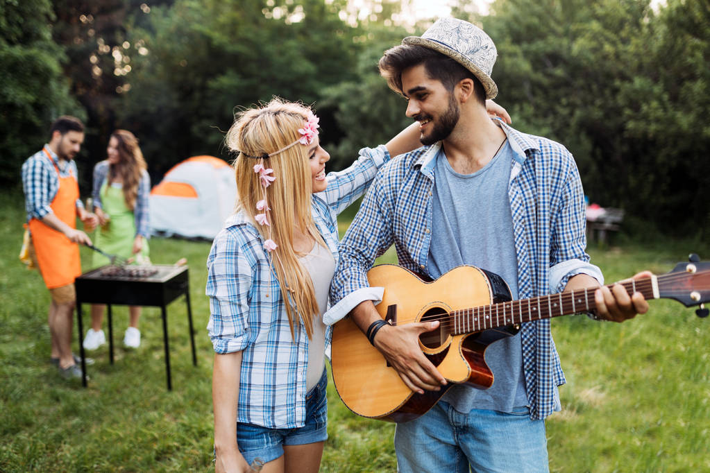 Przystojny mężczyzna gra na gitarze do swojej dziewczyny w przyrodzie - Zdjęcie, obraz