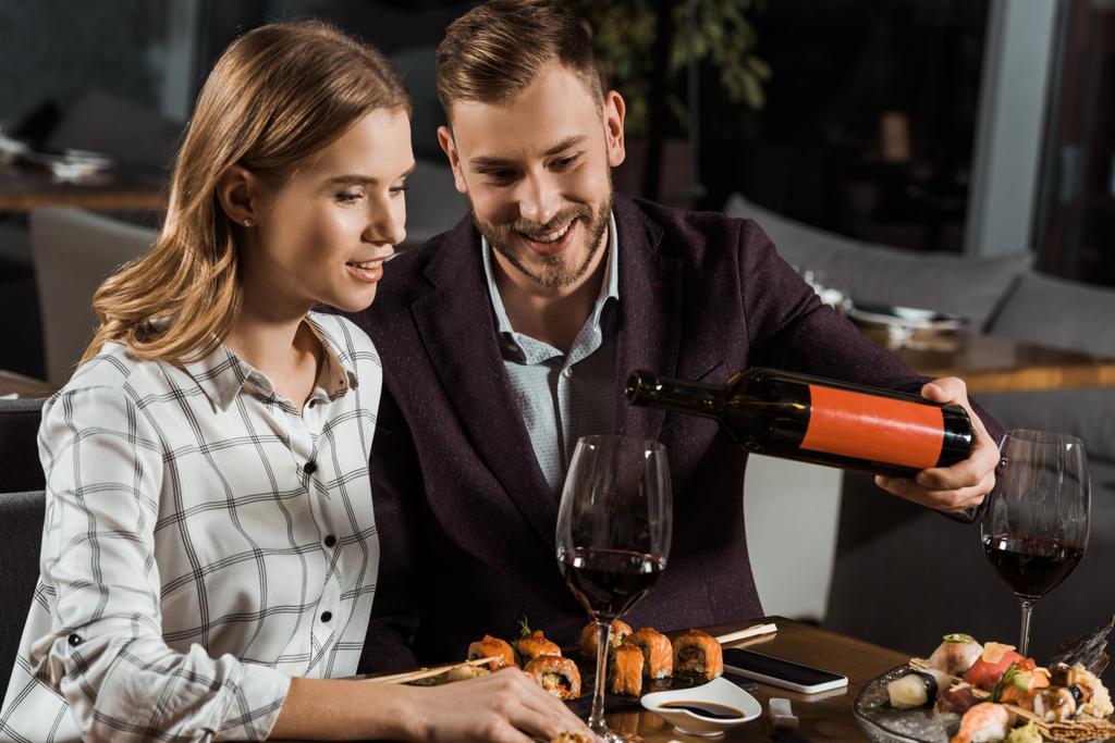 Όμορφος άνδρας έκχυση κρασιού σε ποτήρια ενώ ζευγάρι που έχοντας το γεύμα στο εστιατόριο - Φωτογραφία, εικόνα
