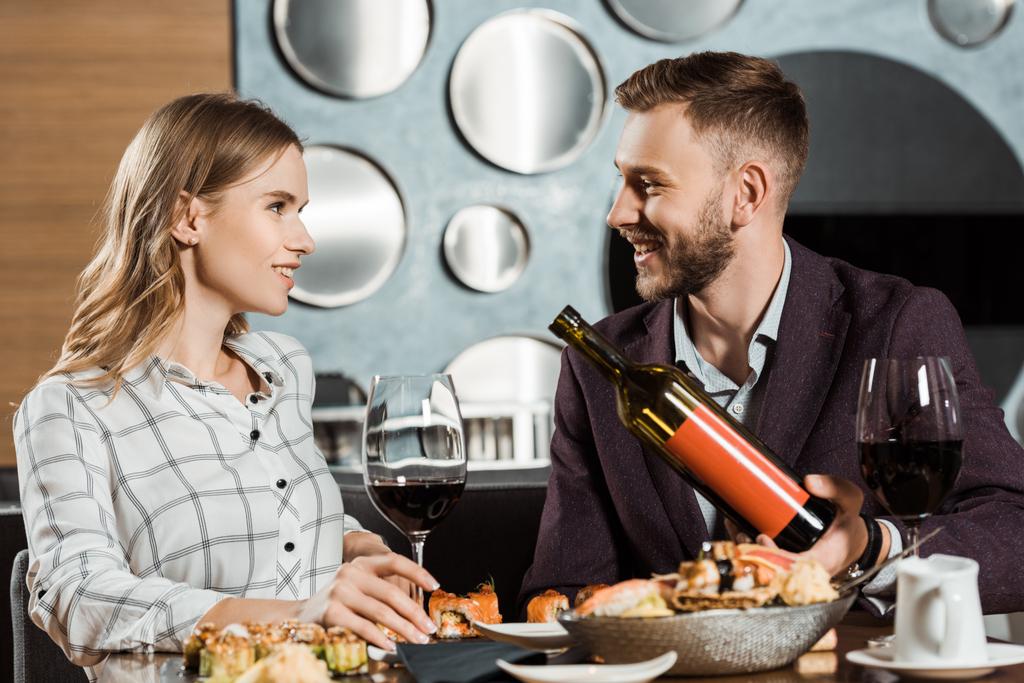 Mies tarjoaa hänen kaunis tyttöystävä viiniä, kun he syövät illallista ravintolassa
 - Valokuva, kuva