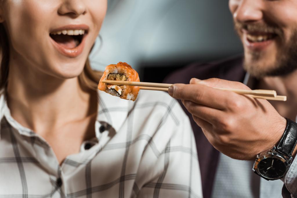 Osittainen näkymä mies ruokkii tyttöystävänsä sushi roll
 - Valokuva, kuva