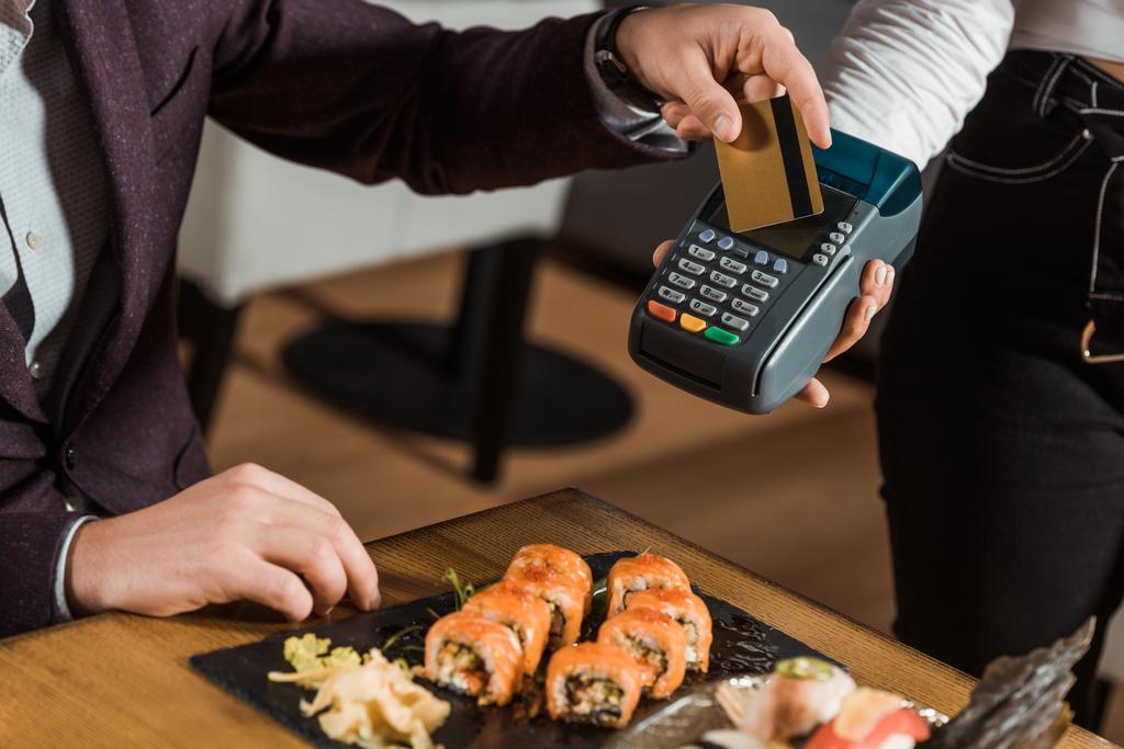 Gedeeltelijke weergave van man betalen per creditcard voor diner in restaurant - Foto, afbeelding