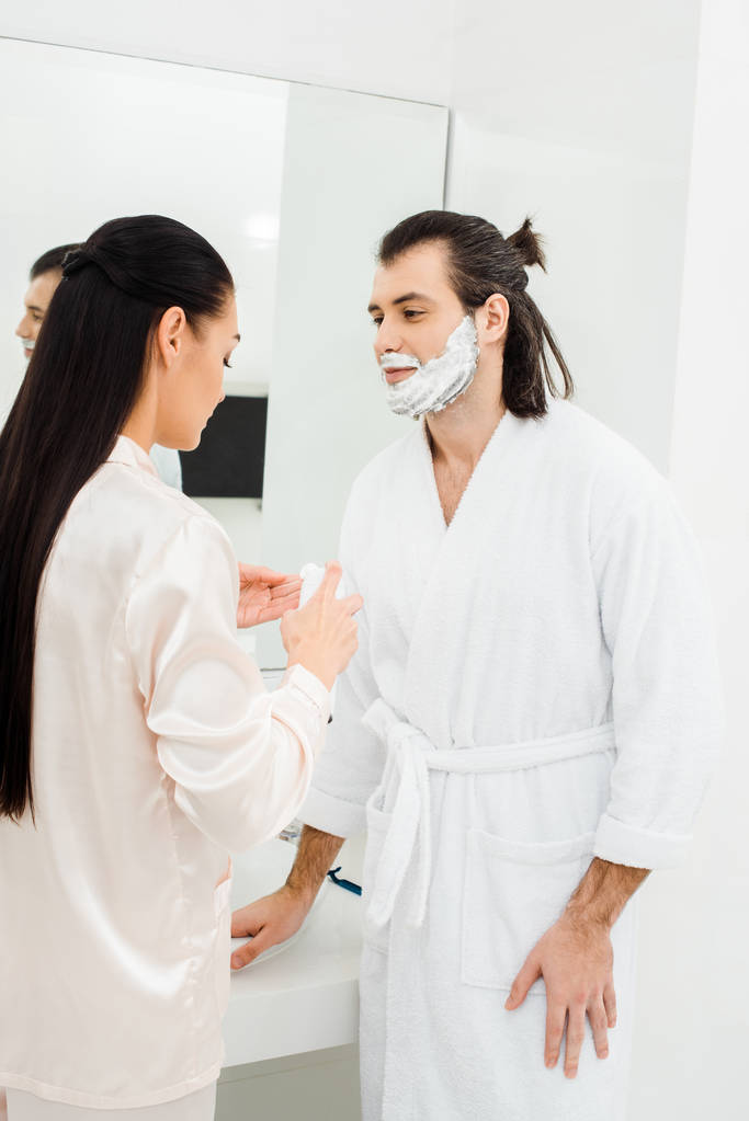 Kobiety stosujące pianki do golenia na twarzy męża  - Zdjęcie, obraz