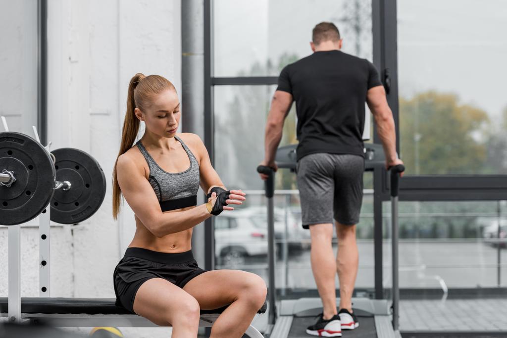 спортсмен тренируется на беговой дорожке, спортсменка в перчатках для тренировки в тренажерном зале
 - Фото, изображение
