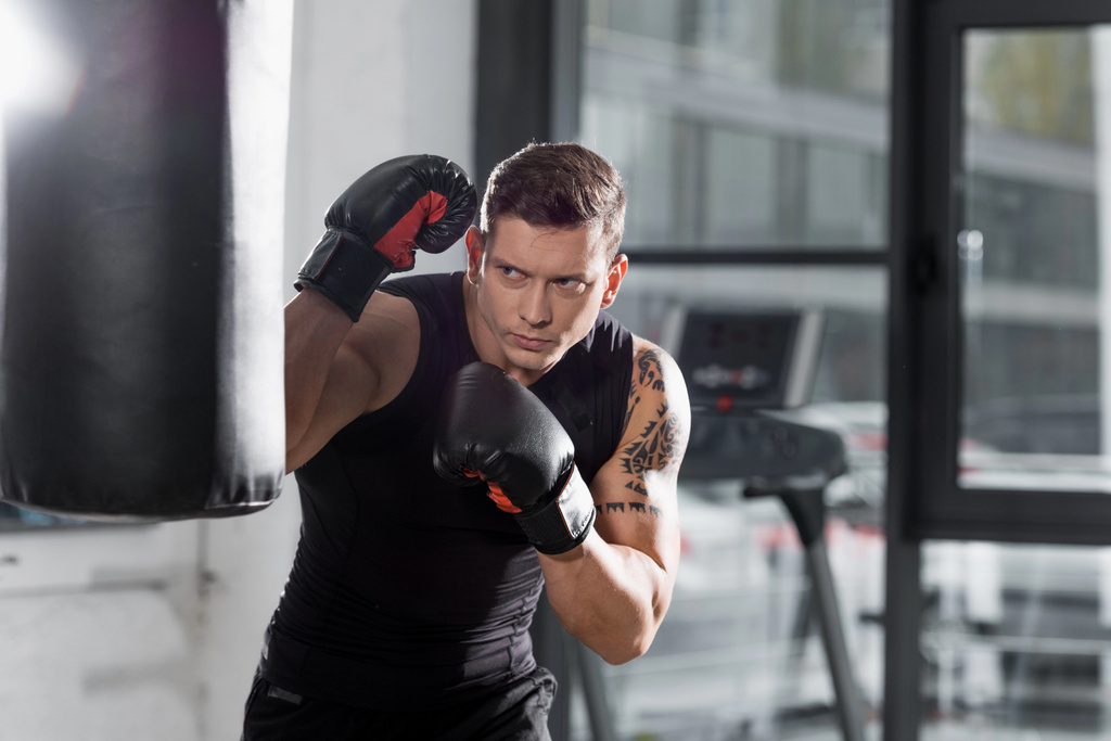 tatuado muscular boxer exercício com saco de perfuração no ginásio
 - Foto, Imagem
