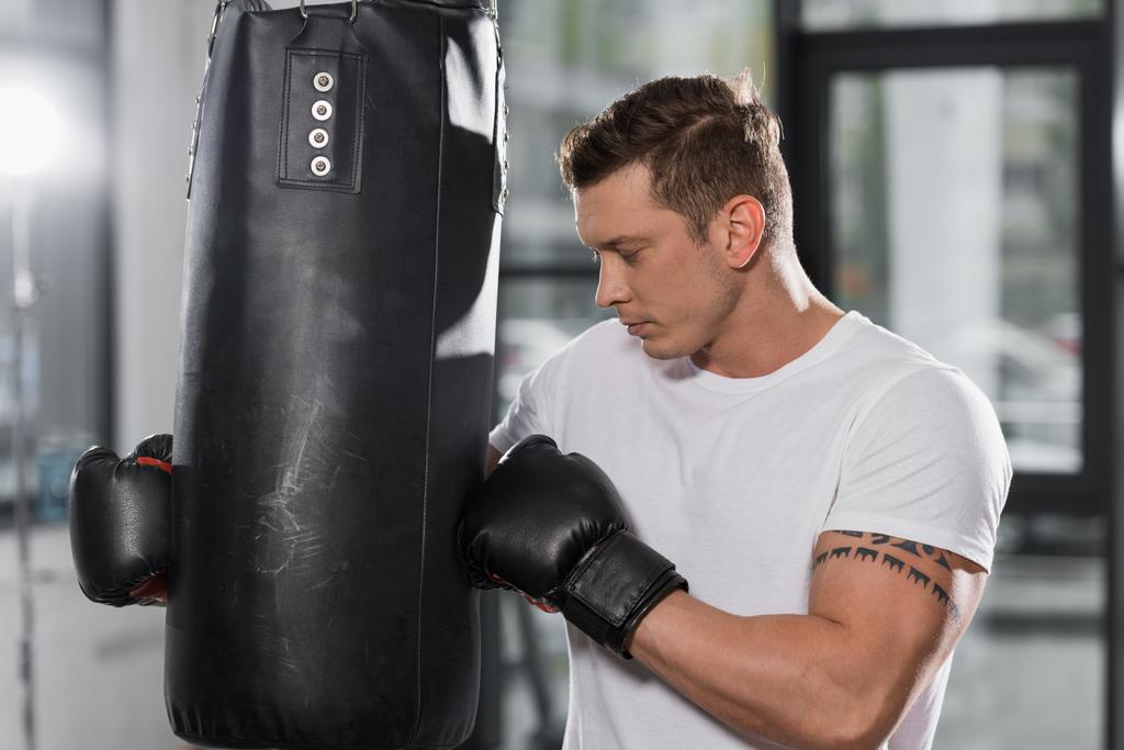 tattooed muscular boxer holding punching bag in gym - Photo, Image