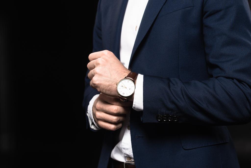 περικοπεί shot του επιχειρηματία σε κομψό κοστούμι με ρολόι στον καρπό που απομονώνονται σε μαύρο - Φωτογραφία, εικόνα