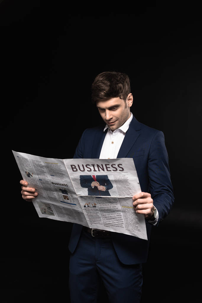 handsome young businessman reading newspaper isolated on black - Photo, Image