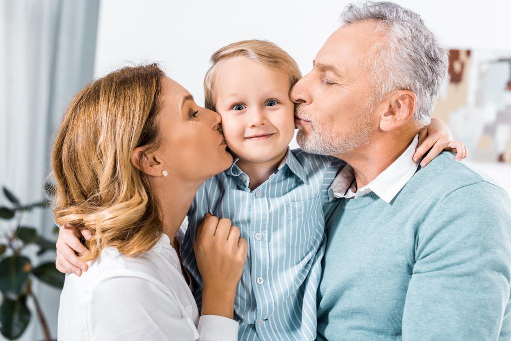 heureux couple d'âge moyen tenant adorable petit-fils et l'embrasser dans les joues
 - Photo, image