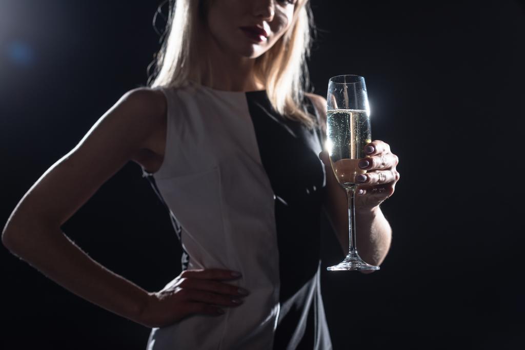 colpo ritagliato di giovane donna che tiene un bicchiere di champagne sul nero
 - Foto, immagini