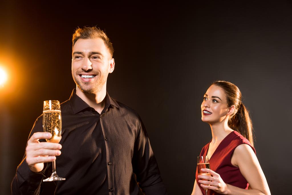 щаслива молода пара в келихах шампанського стоїть на чорному
 - Фото, зображення