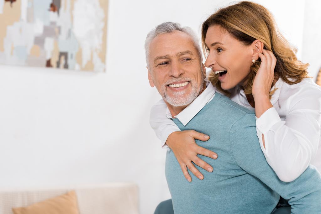 Взрослый мужчина катается на спине к смеющейся жене дома
 - Фото, изображение
