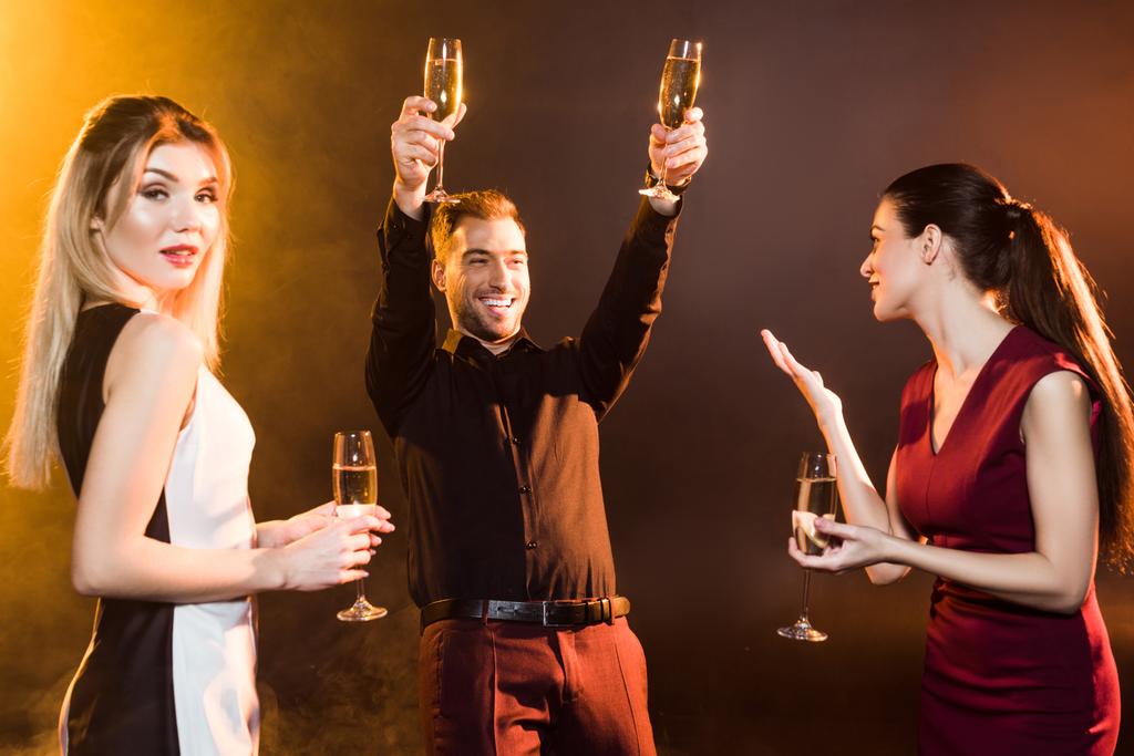group of happy people toasting with champagne glasses under golden light on black - Photo, Image