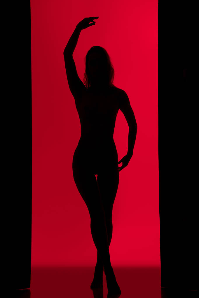 Slim fille silhouette sombre dansant contre le mur rouge
 - Photo, image