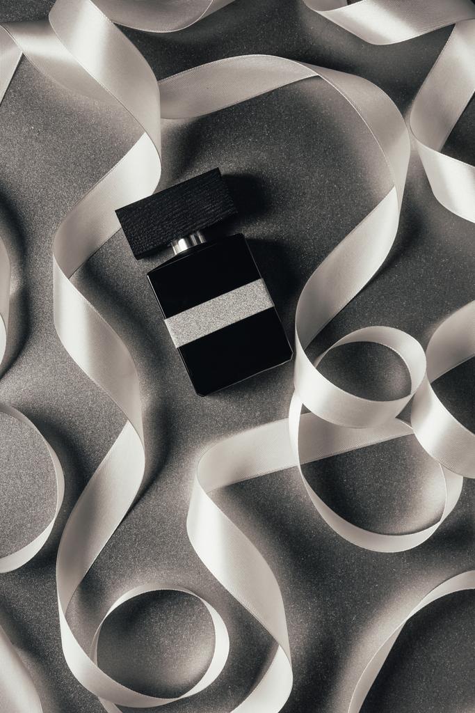 vista superior de perfume embotellado y cintas blancas en gris
   - Foto, imagen