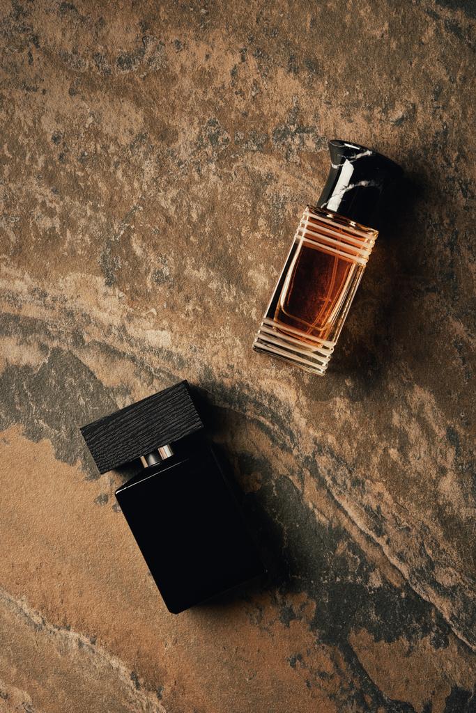 верхний вид бутылок с парфюмерией на коричневую выветренную поверхность
  - Фото, изображение