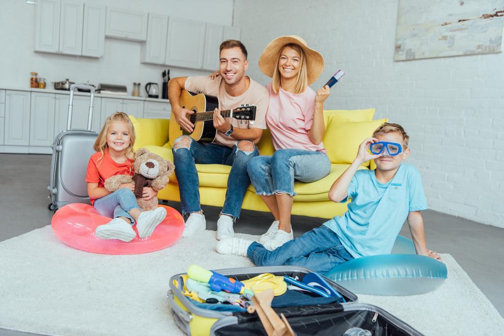 счастливая семья с паспортом, упаковка багажа для летних каникул и имеющие большое время, концепция путешествия
 - Фото, изображение