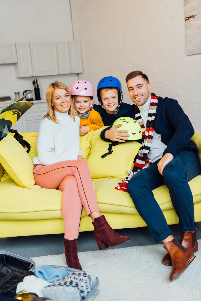 familia feliz sentado en el sofá con accesorios de esquí y embalaje para las vacaciones de invierno, concepto de viaje
 - Foto, imagen