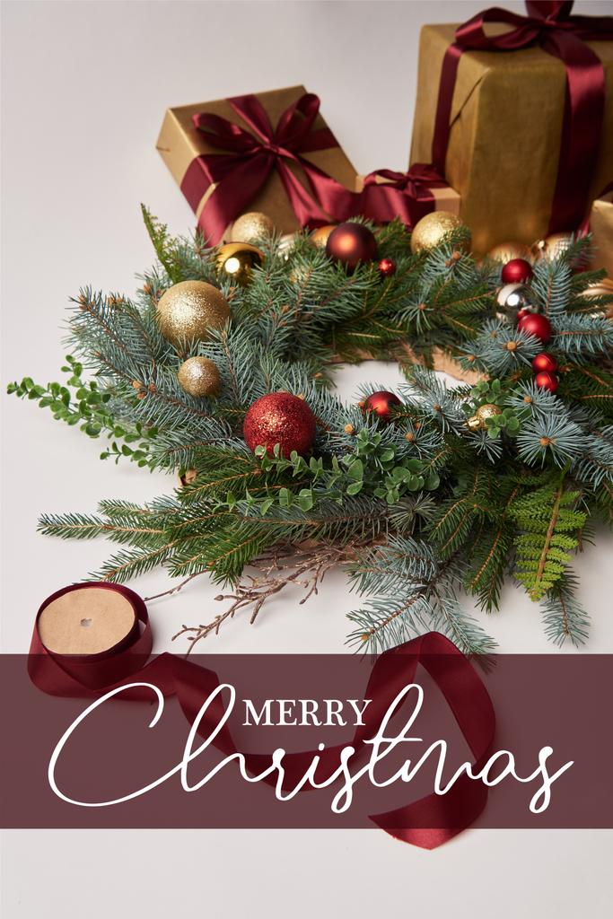 Karácsonyi ajándék dobozok, fenyő koszorú és szalag orsó elszigetelt fehér "boldog karácsonyt" felirat, dekoráció - Fotó, kép