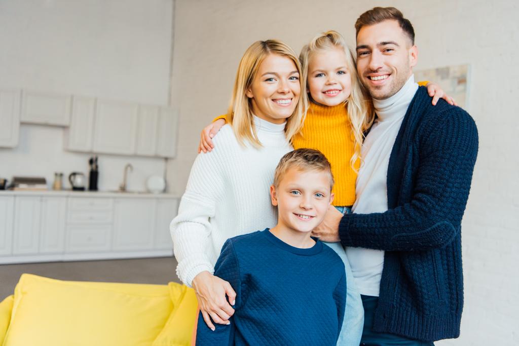 glückliche Familie in lässiger Kleidung, die sich umarmt und in die Kamera schaut  - Foto, Bild