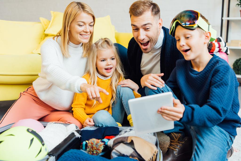 família feliz ter grande momento, usando tablet digital e embalagem para férias de inverno
 - Foto, Imagem